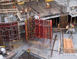 Industrial construction site with workers in high visibility clothing at a steel framework structure.